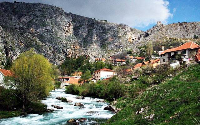 River and village houses below the mountains near Livno