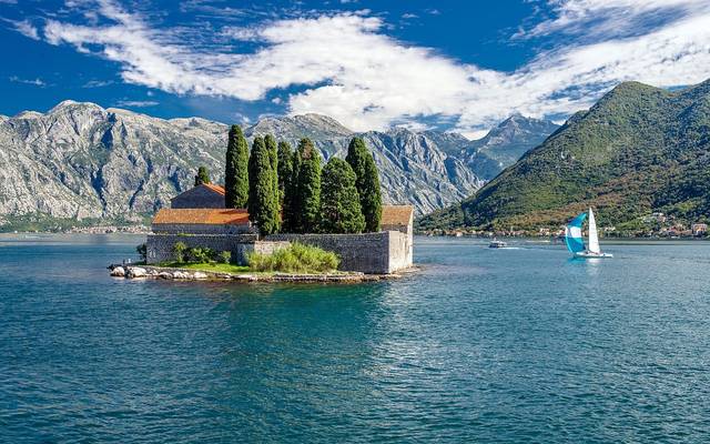 Islet with a church in the Bay of Kotor, mountains behind