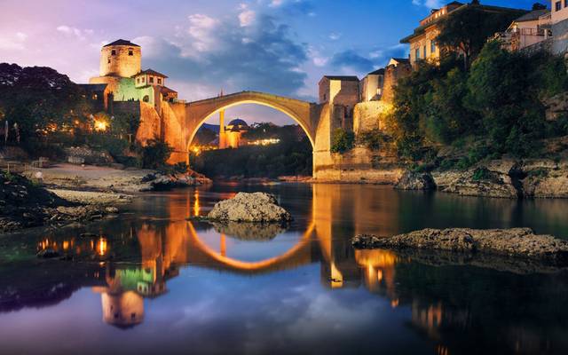 Mostar's Old Bridge over the Neretva river, lit at dusk