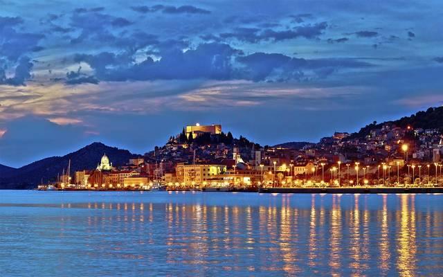 Šibenik old town lit up across the bay at dusk