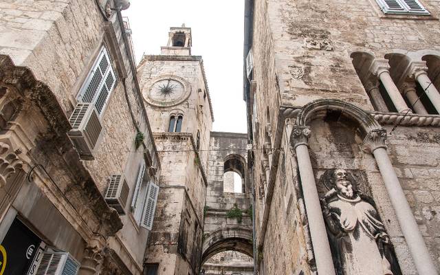 Narrow stone street with a clock tower in Split's Old Town